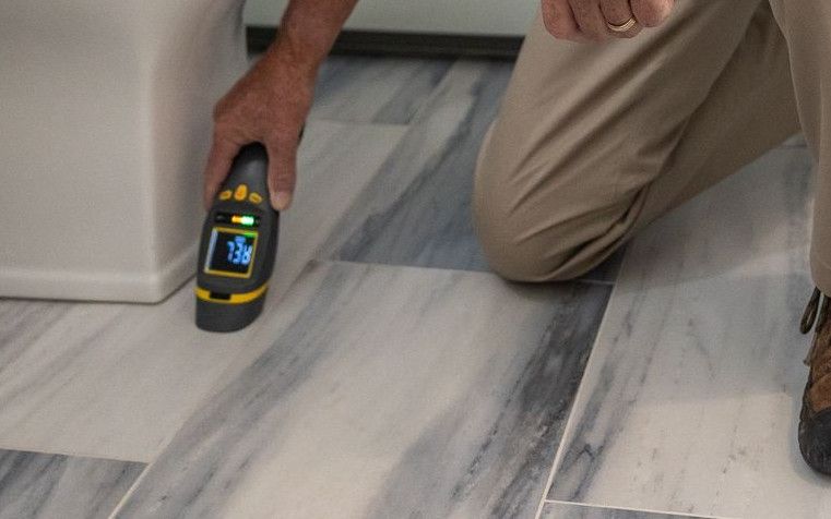A senior man using a device to inspect a bathroom for maintenance or repair.